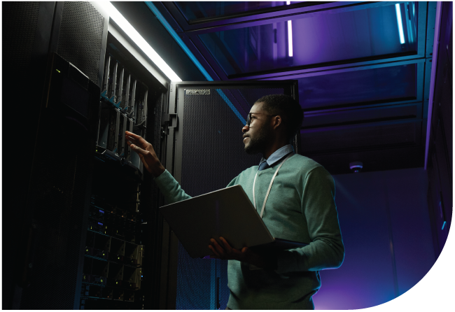 Technician holding a laptop while troubleshooting server room equipment.