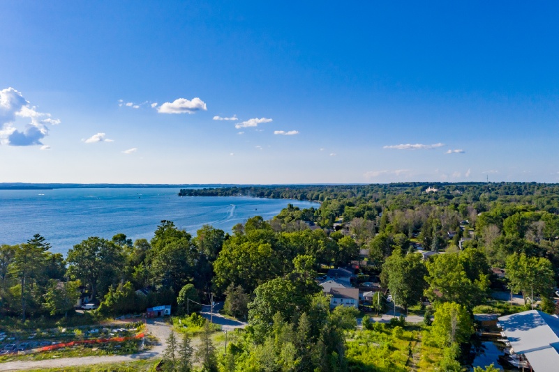 4 Aerial view of residential homes along a tree-lined lakeshore with a small boat in the distance.